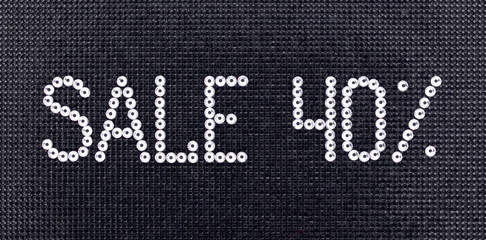 Word SALE is made rhinestones crystal color on a black canvas background.
