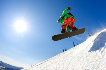 Snowboarder jumping from the springboard against the sky