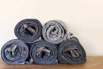 stack of roll old fade denim on wooden surface and concrete background. vintage clothing fashion concept.