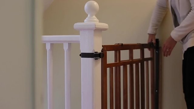 Mother Closes Baby Safety Gate At Top Of Stairs