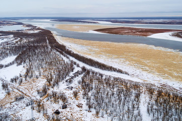 This is aerial view of the thick spruce forest with a big river in a cold winter day.