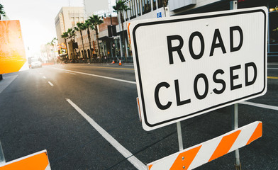 Road closed sign and traffic cone in the street. Traffic control sign road closed in the city. Road closed sign on Hollywood Boulevard.