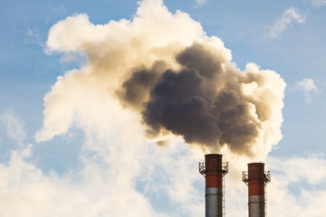 Stream of dark smoke from the chimney of factory in the industrial district