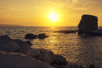 Rocky seashore in evening. Golden sunset over the sea