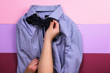 The girl tries on a bow tie to bright men's shirt. Flat lay. The view from the top.