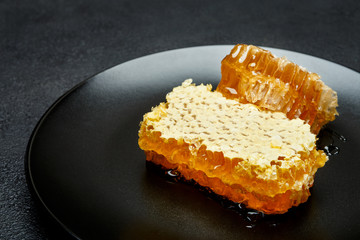 Honeycomb with honey on plate. dark concrete background