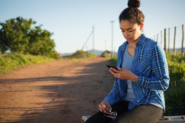 Woman using her mobile phone while sitting on suitcase