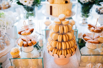 Colorful table with sweets and goodies for the wedding party reception, decorated dessert table. Delicious sweets on candy buffet. Dessert table for a party. cakes, cupcakes.