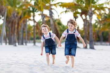 Two little kids boys having fun on tropical beach