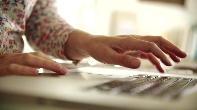 Close-up on woman's hands typing on the keys of a laptop computer