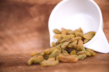 Closeup image of raisin in a white cup on wooden background