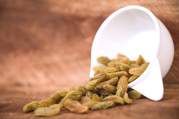 Closeup image of raisin in a white cup on wooden background