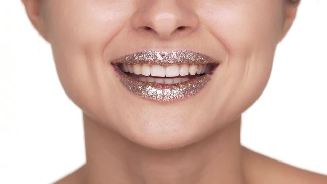 Extreme close up portrait of surprised woman with shiny golden lipstick on lips saying WOW being excited and contented over white background. Facial expressions