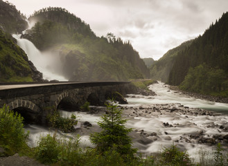 Fototapeta na wymiar Cascada de Låtefossen, en la zona de ODDA, Noruega, verano de 2017. Lugar famoso turístico, en el que dos corrientes de agua se unen en el medio al bajar bajo el puente.