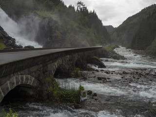 Fototapeta na wymiar Cascada de Låtefossen, en la zona de ODDA, Noruega, verano de 2017. Lugar famoso turístico, en el que dos corrientes de agua se unen en el medio al bajar bajo el puente.