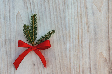 Christmas green spruce branch with a red ribbon on a wooden background