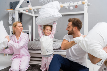 happy young family fighting with pillows in kid bedroom
