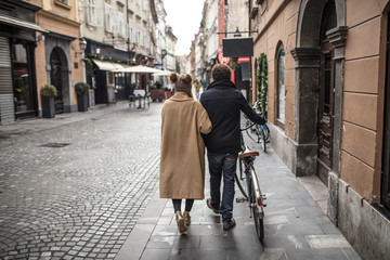 young couple walking on the streets of a lovely little city with a bike