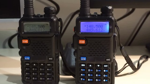 Two black handled portable walkie- talkie radio transmitter working and flashing in the dark