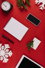 flat lay with office supplies, decorative snowflake and christmas toys isolated on red