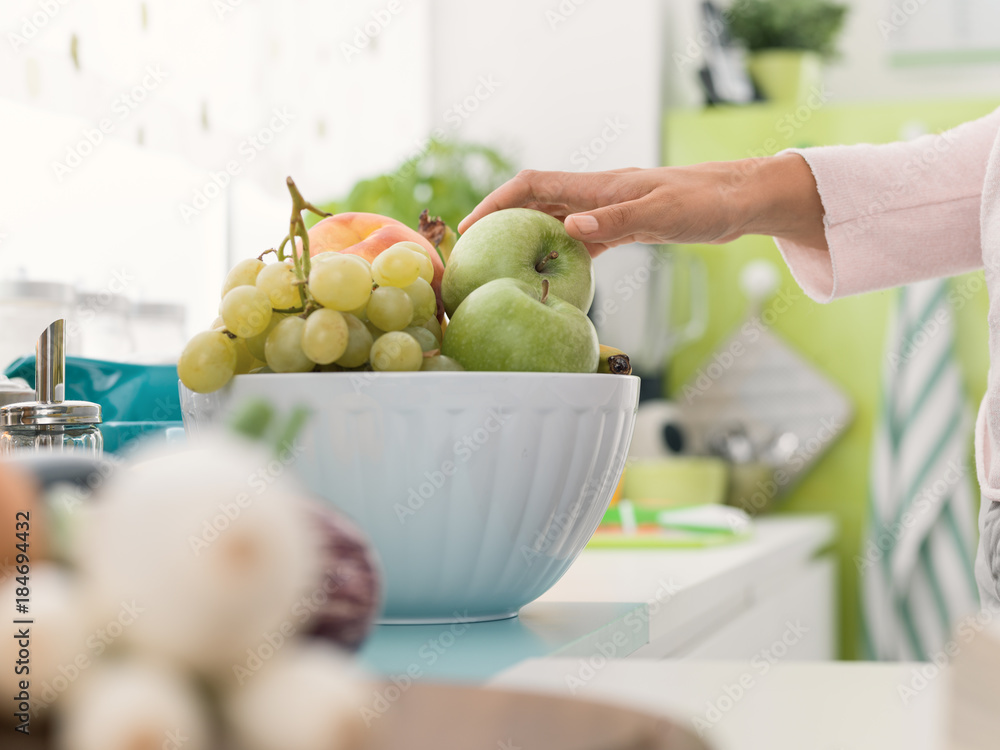 Wall mural Woman taking an apple from a fruit bowl