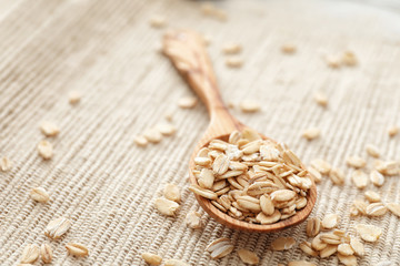 Oatmeal flakes and wooden spoon on fabric