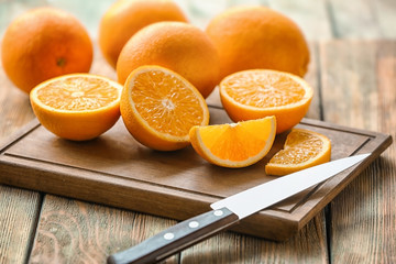 Board with fresh cut oranges and knife on table