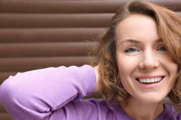 Beautiful smiling woman near color wall