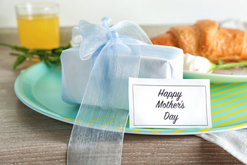 Gift box and card with text HAPPY MOTHER'S DAY on table