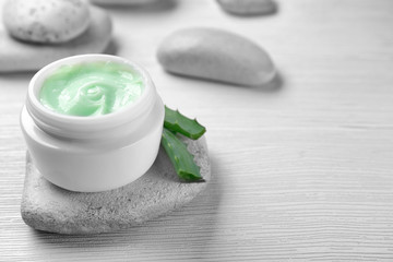 Jar of body cream and aloe leaves on light background, closeup