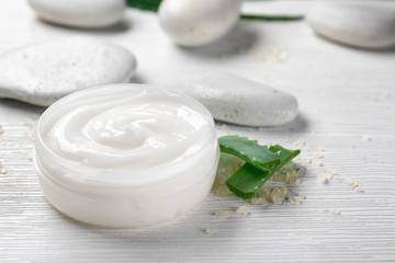 Obraz na płótnie Canvas Jar of body cream and aloe leaves on light background, closeup