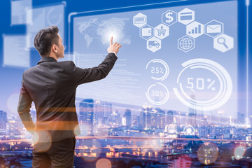 The abstract image of business man point to the hologram on the rooftop and blurred cityscape is backdrop. the concept of communication, network, business, cyber, economy and internet of things.