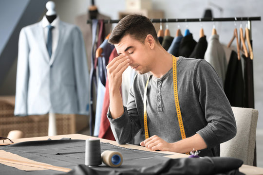 Tired young tailor in atelier