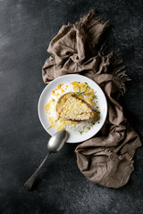 Traditional french onion soup with cheese and bread served in white ceramic plate with rosemary, spoon and textile napkin over black texture background. Top view, copy space