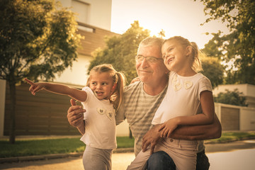 Grandfather with his granddaughters on street looking something fanny. © liderina