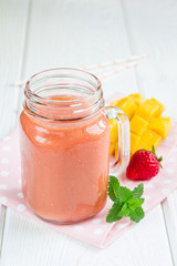 Healthy smoothie with strawberry, mango and banana in glass jars, vertical, copy space