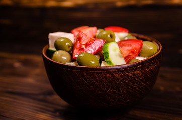 Greek salad in a bowl on wooden table