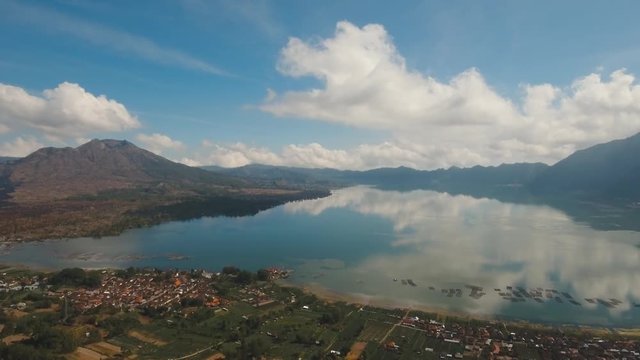Aerial view Lake among the mountains with a reflection on the surface of the blue sky and clouds, Bali, Indonesia. Mountain landscape with volcanoes, lake, sky and clouds. 4K video. Travel concept