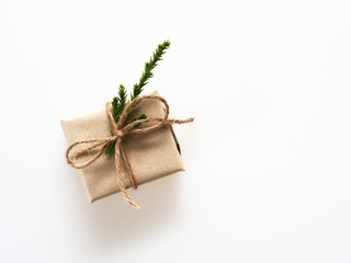 A present or gift box wrapped by rough brown recycled paper and tied with brown hemp rope ribbon with pine branch isolated on white background with concept of green and environment and nature friendly