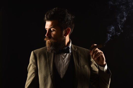 Businessman with shy face expression smokes cuban cigar.