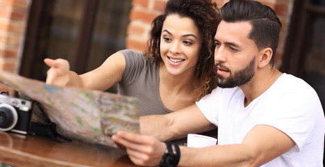 Fototapeta premium Young tourists having coffee at cafe and reading map