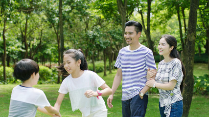 Asian family enjoying summer weekend in park walking & smiling