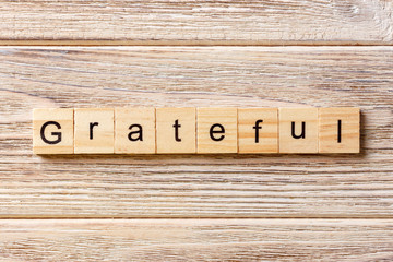 Grateful word written on wood block. Grateful text on table, concept
