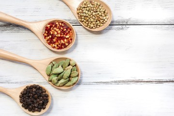 Various spices in wooden spoon on dark black background, top view