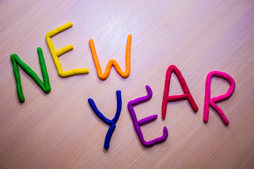 New Year message from colorful bright plasticine on a light wooden background. Colorful bright New Year background 