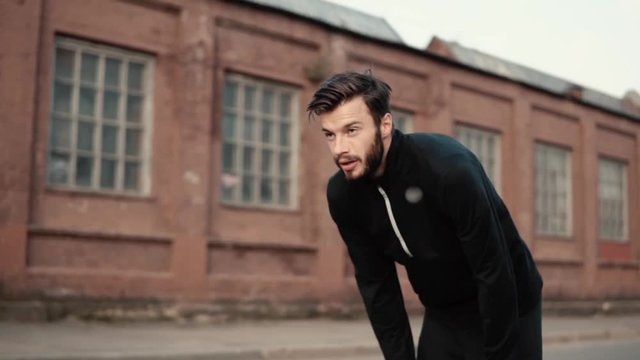 Slow motion tired man rising and standing strong. Front view close up handsome caucasian bearded male breathing heavily.