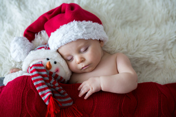 Little sleeping newborn baby boy, wearing Santa hat