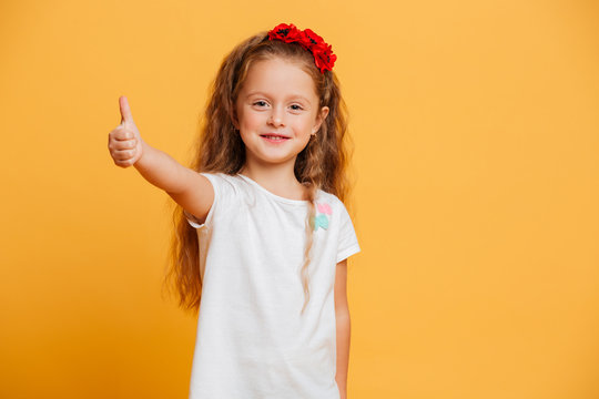 Little girl child standing isolated showing thumbs up.
