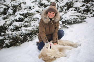 Beautiful girl playing with her dog in the snow. Golden Retriever