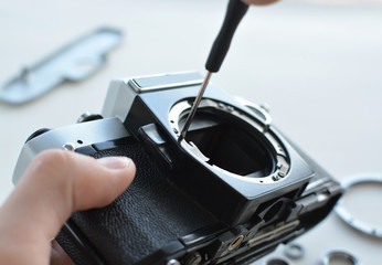 Engineer technician checks optics and carry out maintenance and cleaning of the broken camera at the service center. Top view of the workplace and the hands of the engineer.